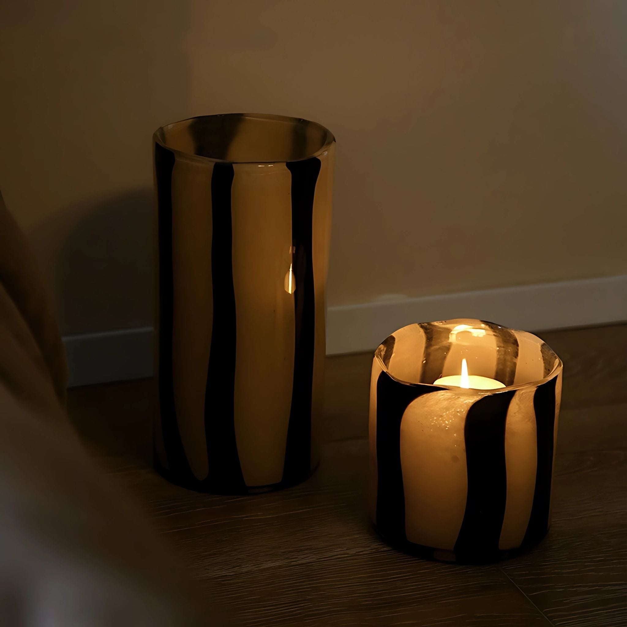 Decorative glass vessel candleholder and vase with stripes in beige and black.
