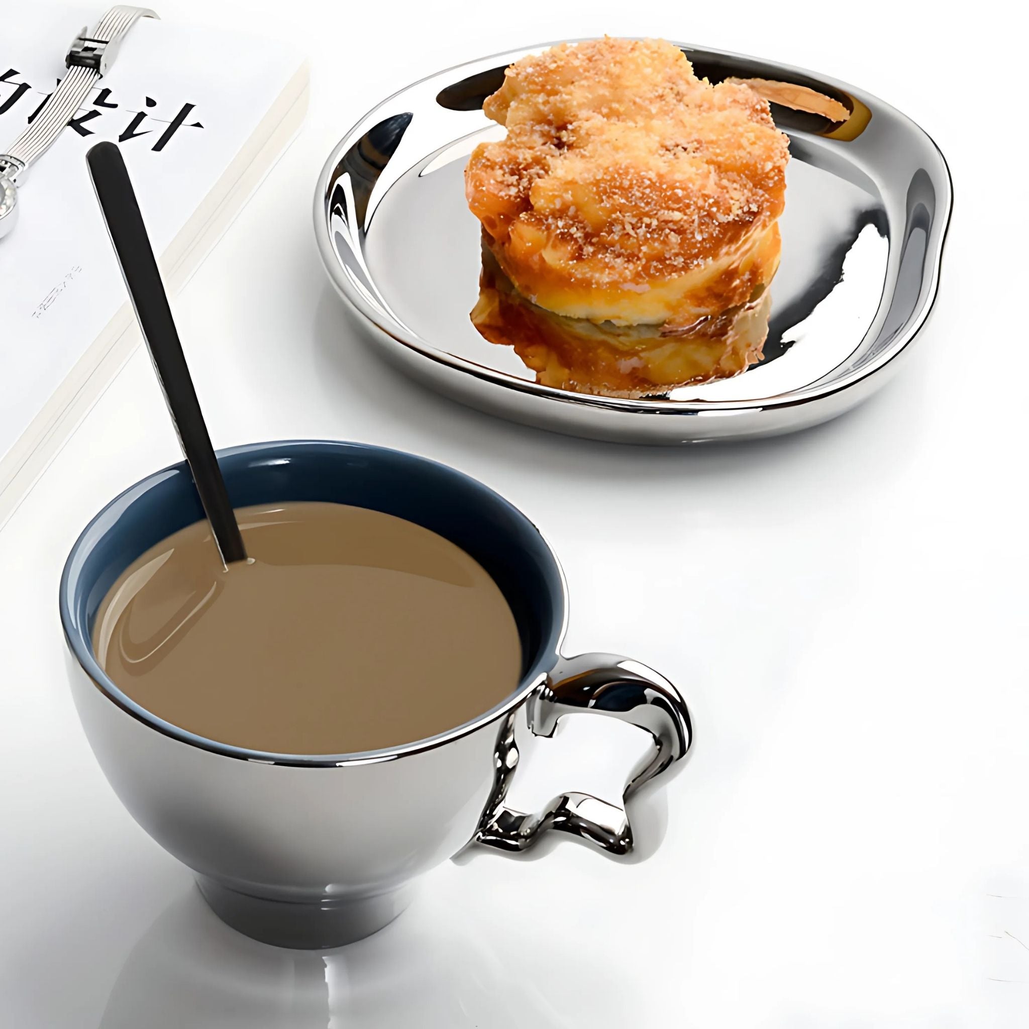 Ceramic silver chrome tea set cup and plate with coffee and dessert on tabletop.