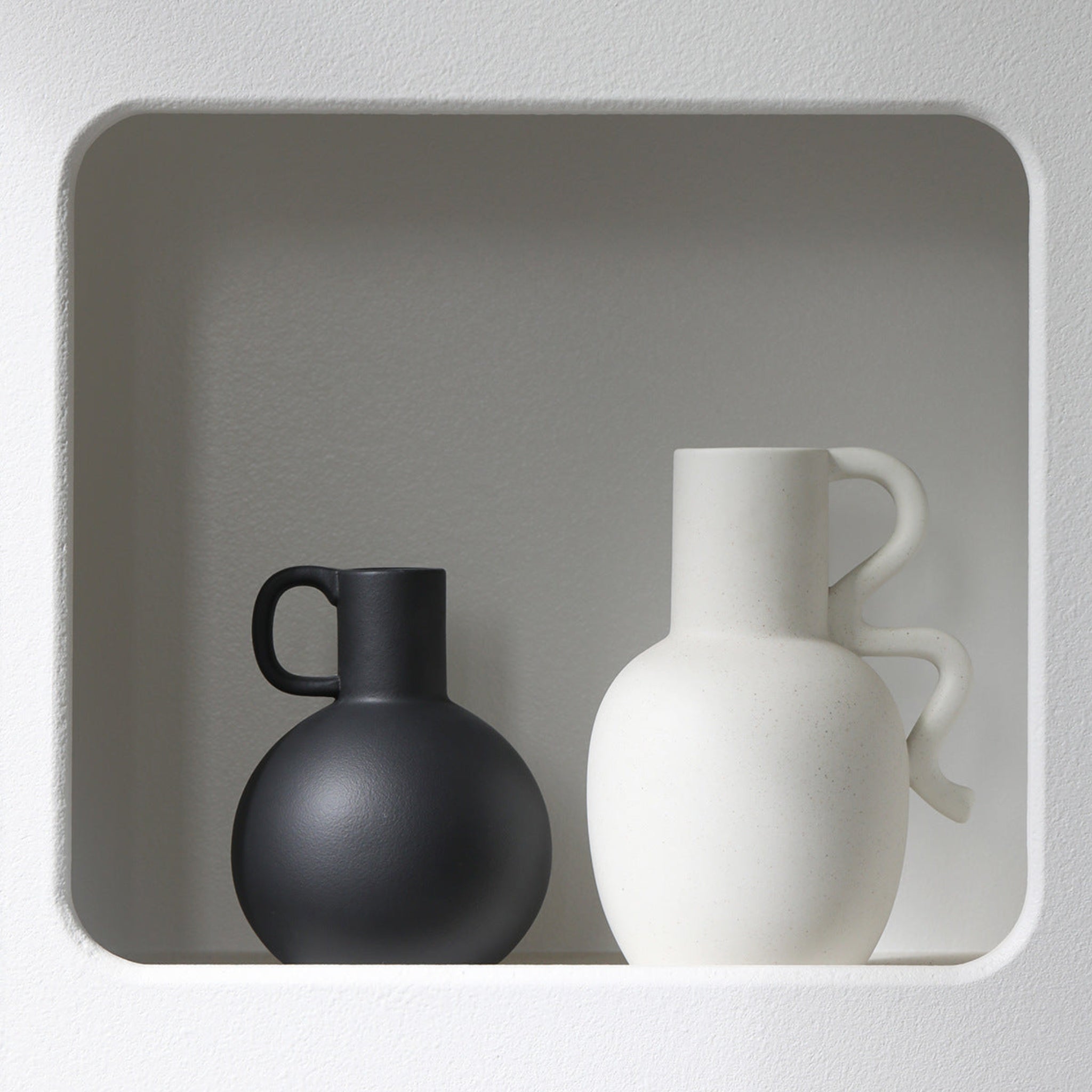 Black and white ceramic bottle pitcher vases on shelf.