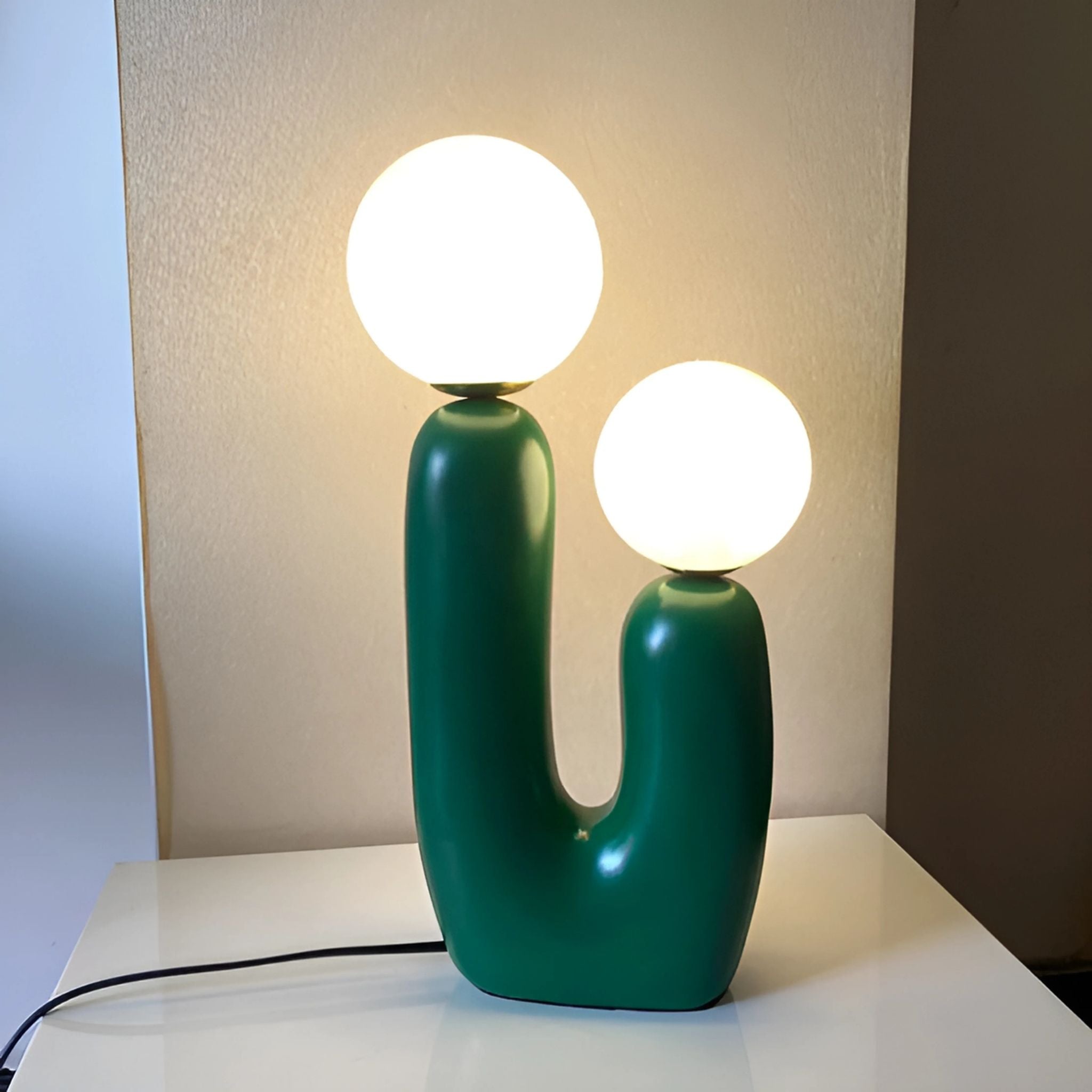 Green table lamp with two, large light bulbs.