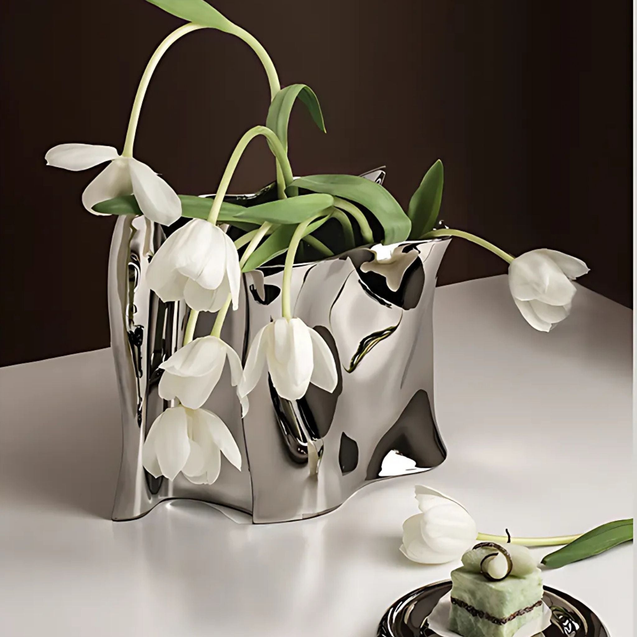 A silver chrome electroplated decorative table vase with white flowers.