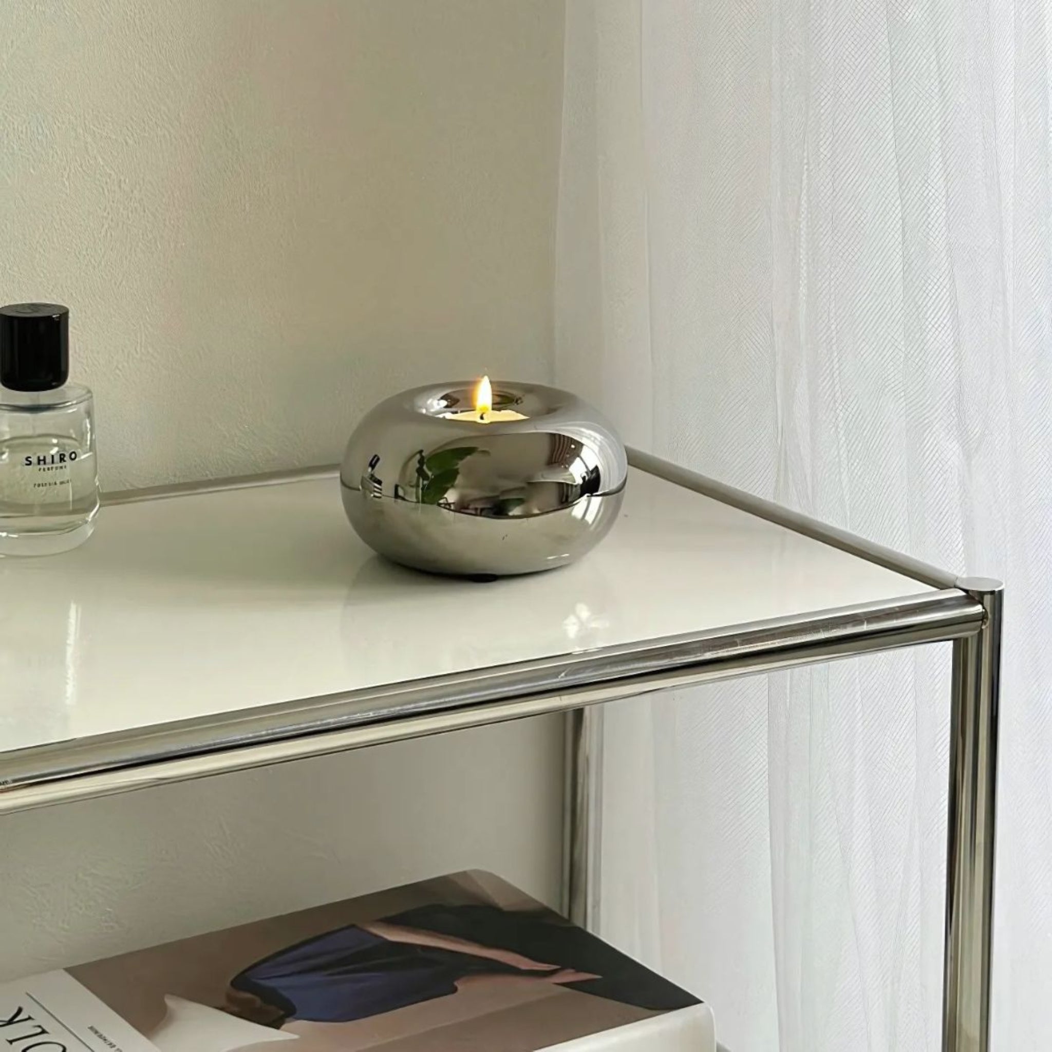 Modern home decor silver spherical candleholder on white table.