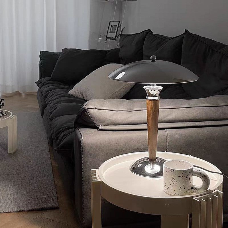 Living room with coffee table holding a wooden and silver metallic table lamp and coffee mug.