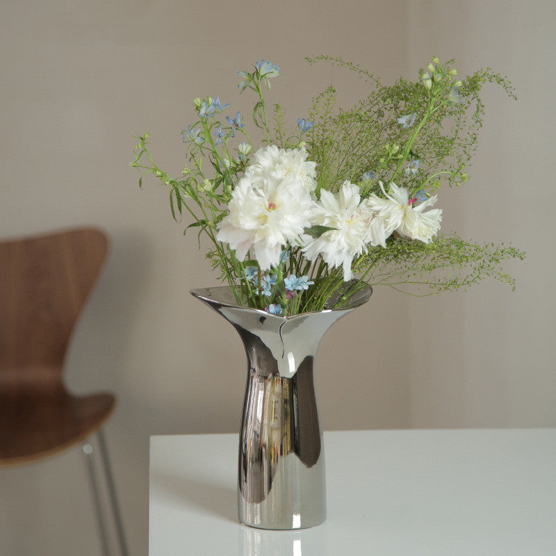 White table counter with silver vase with white flowers.
