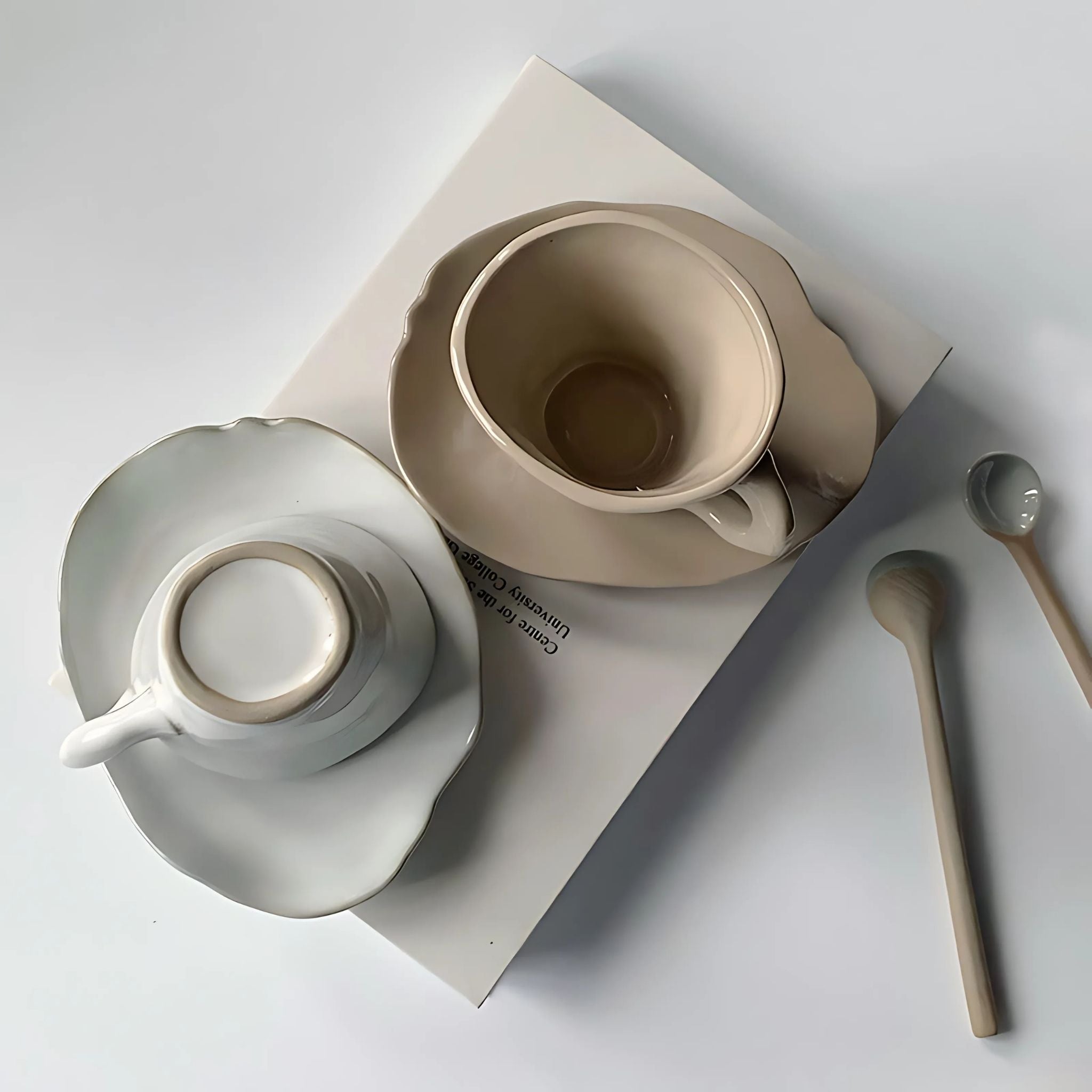 A white and beige ceramic coffee mug with saucer with irregular, modern design.