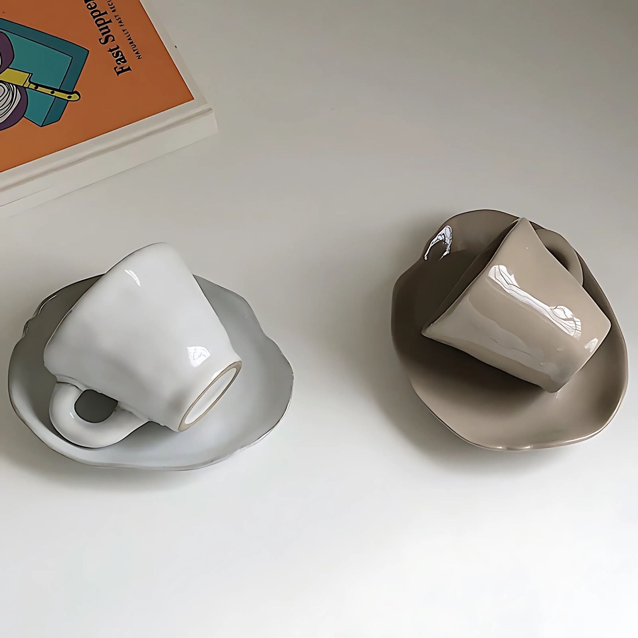 White and beige ceramic coffee mug and saucer on top of table.