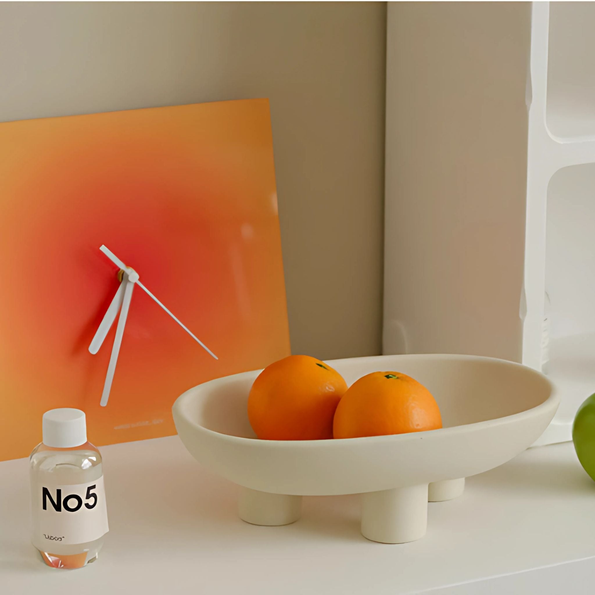 White, decorative fruit tray with three legs, holding oranges.