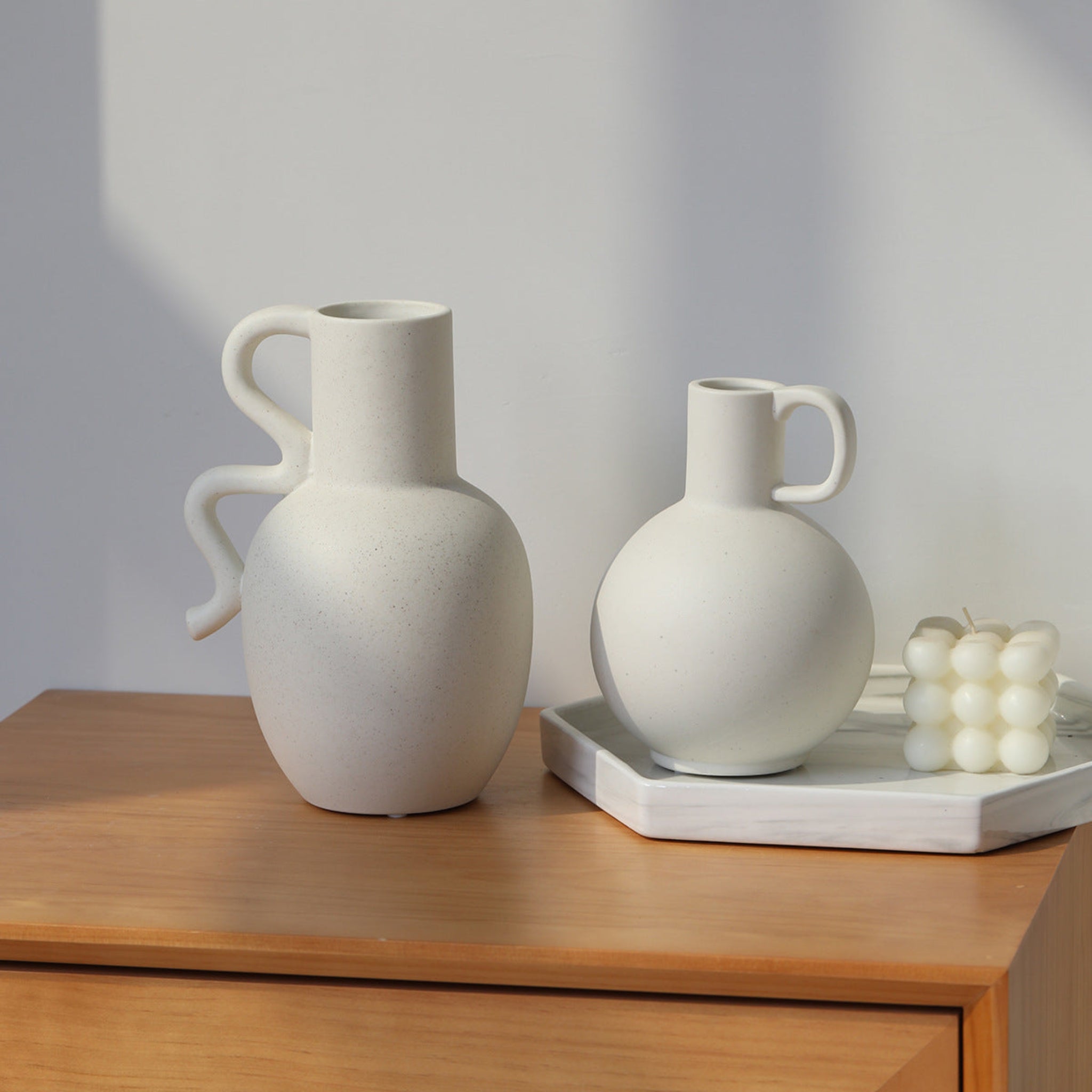 White, ceramic pitcher vases on table top.