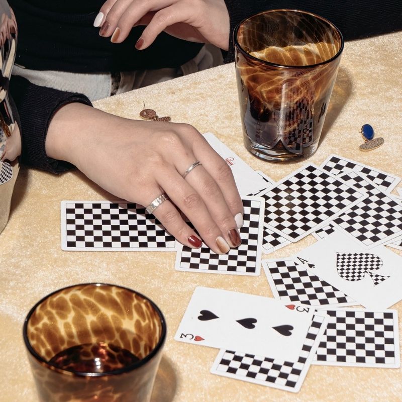 Table with playing cards and brown tortoiseshell drinking glasses.
