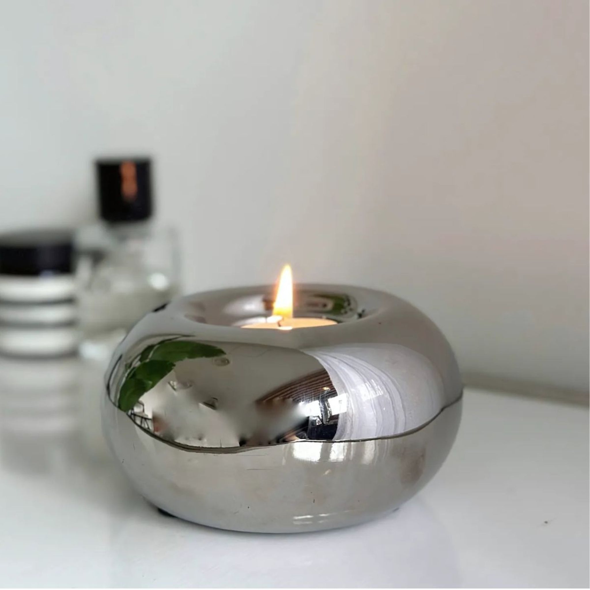 Silver spherical chrome orb candle holder on table.