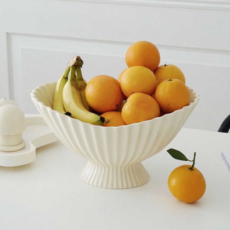 Cream white minimalist elegant style ceramic fruit bowl with oranges and bananas on dining table.