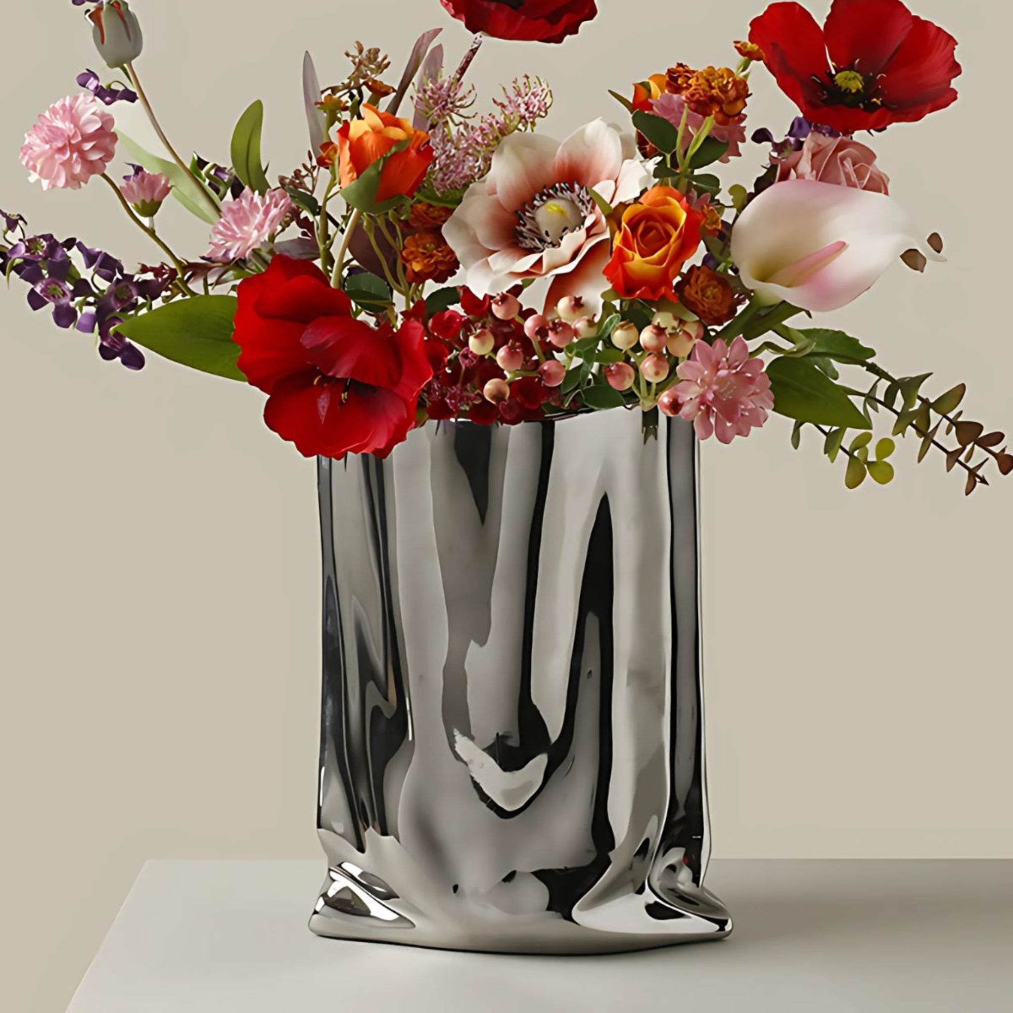 A large red and pink flower bouquet in an electroplated silver chrome bag vase.