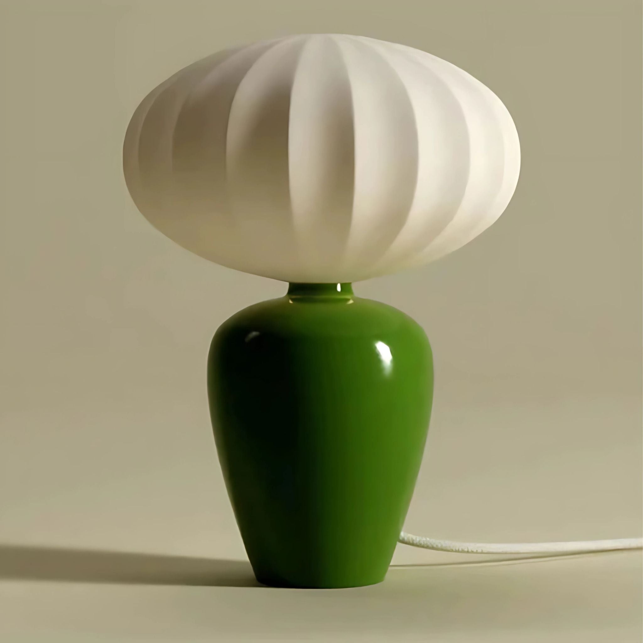 Decorative table lamp with green, ceramic base and white, round, lamp shade.