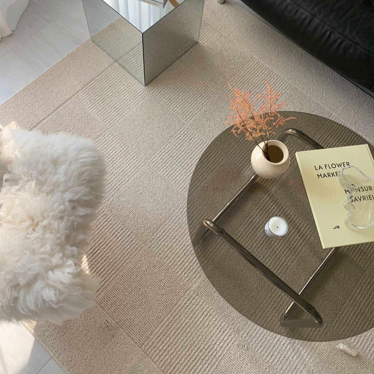 Living room with a beige floor carpet, a dark grey glass coffee table and a white fur chair.