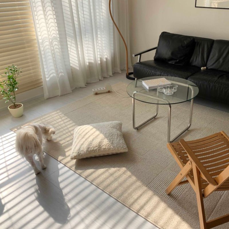 Living room with a black sofa, a glass coffee table, wooden chair and a floor carpet in beige and a dog.