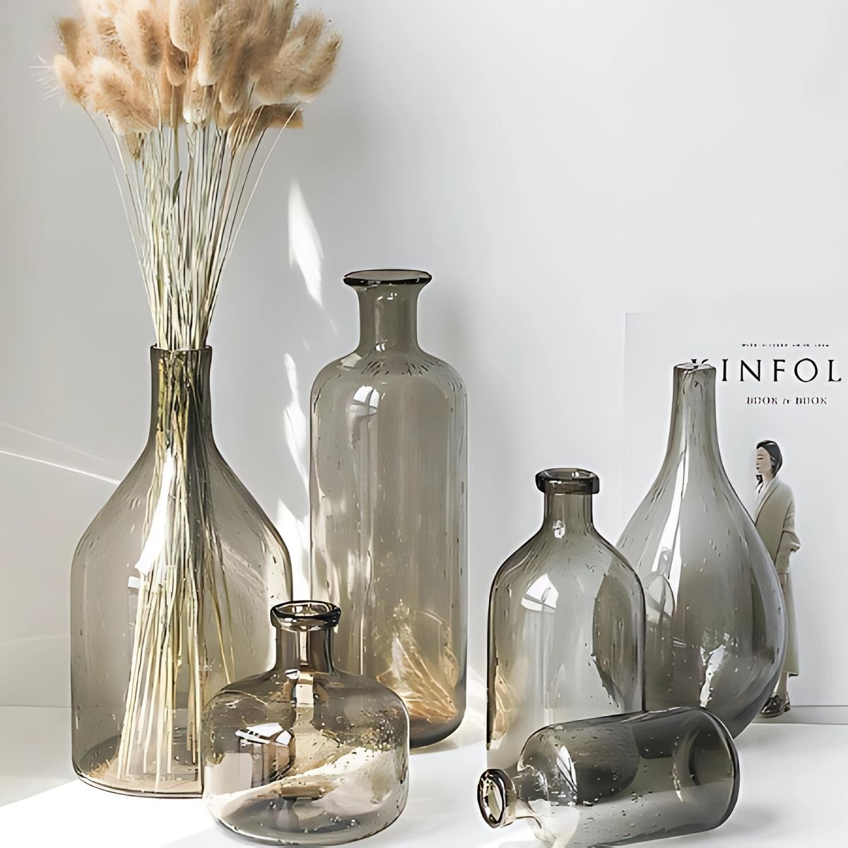 A collection of grey glass vases in different designs on a table.