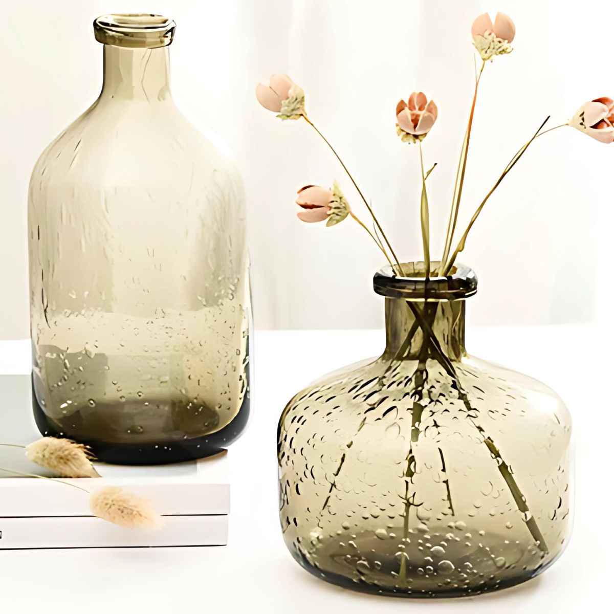 Grey glass vases on table with flowers.