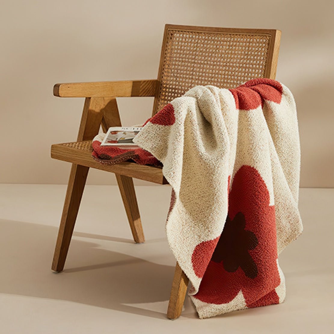 Wooden chair with white throw blanket with red floral pattern.