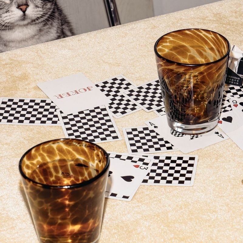 Tortoiseshell drinking glass on a table with playing cards.