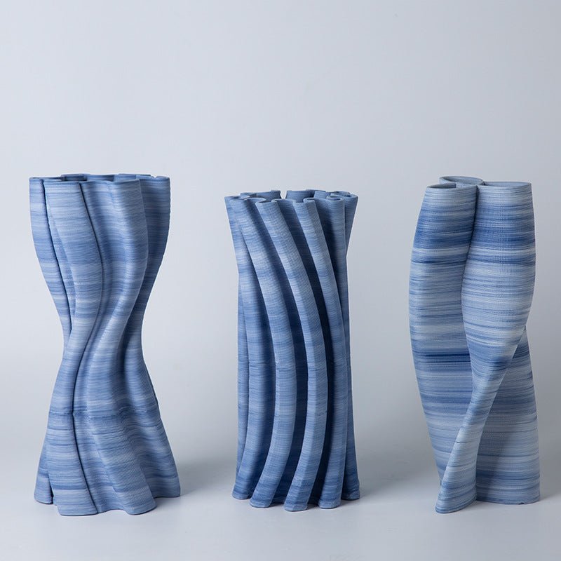 Three, blue, ceramic vases with a twist, irregular design.