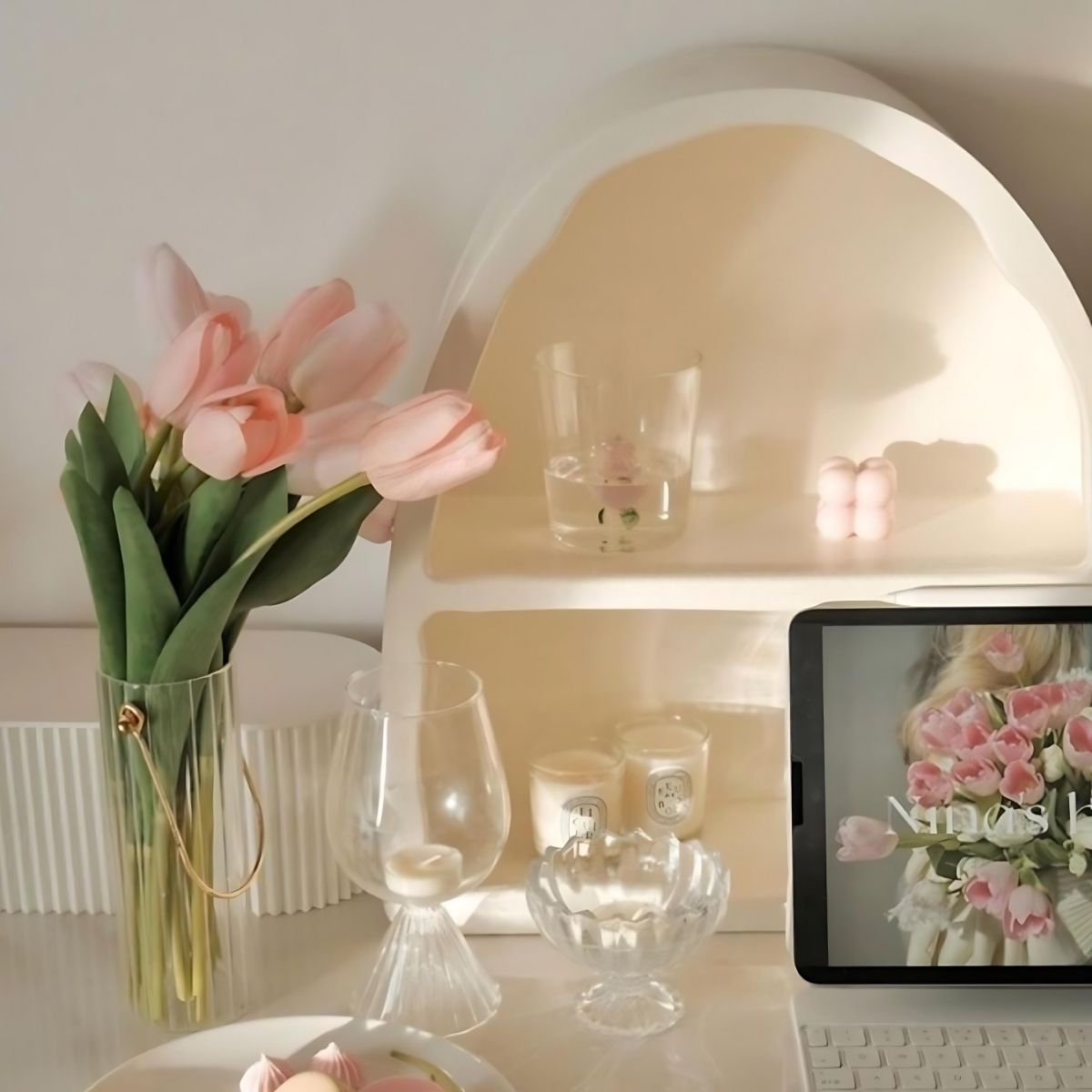 Decorative white arch shaped storage shelf and glass vase with pink tulip flowers.