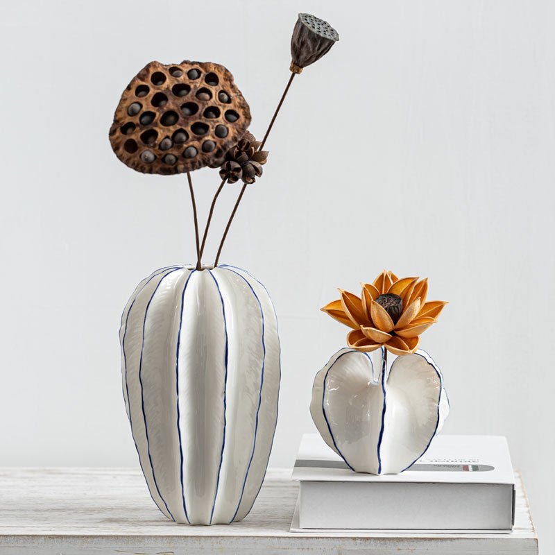 White ceramic vases on table with flowers.