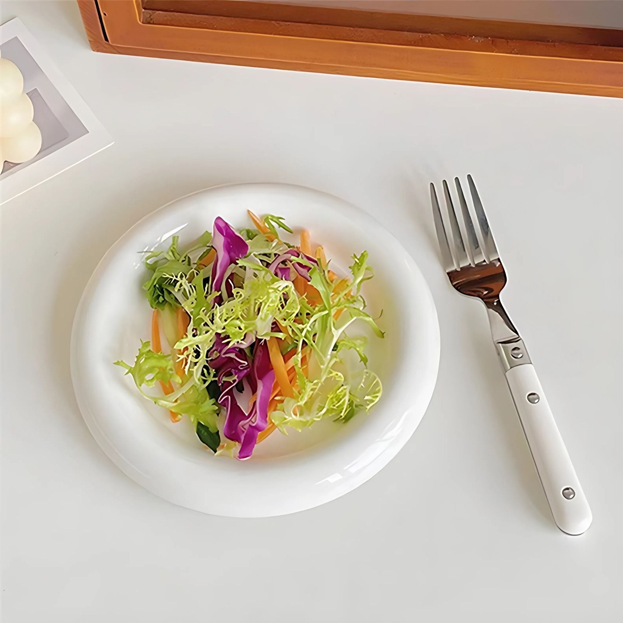 White, chunky, ceramic tableware plate with salad.