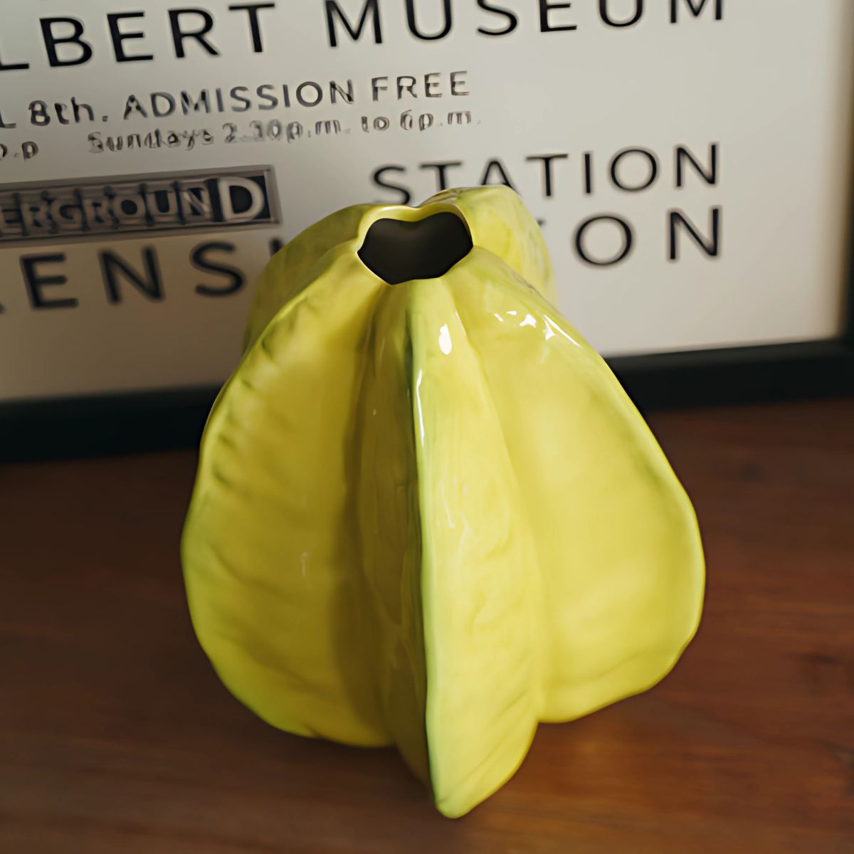 A yellow, starfruit design vase standing on top of wooden table.