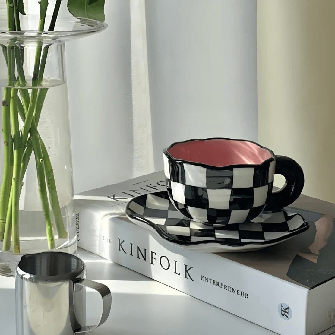 Black white pink irregular ceramic mug and saucer on table with book
