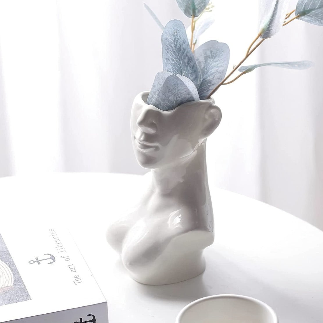 Elegant, ceramic face vase with blue flowers