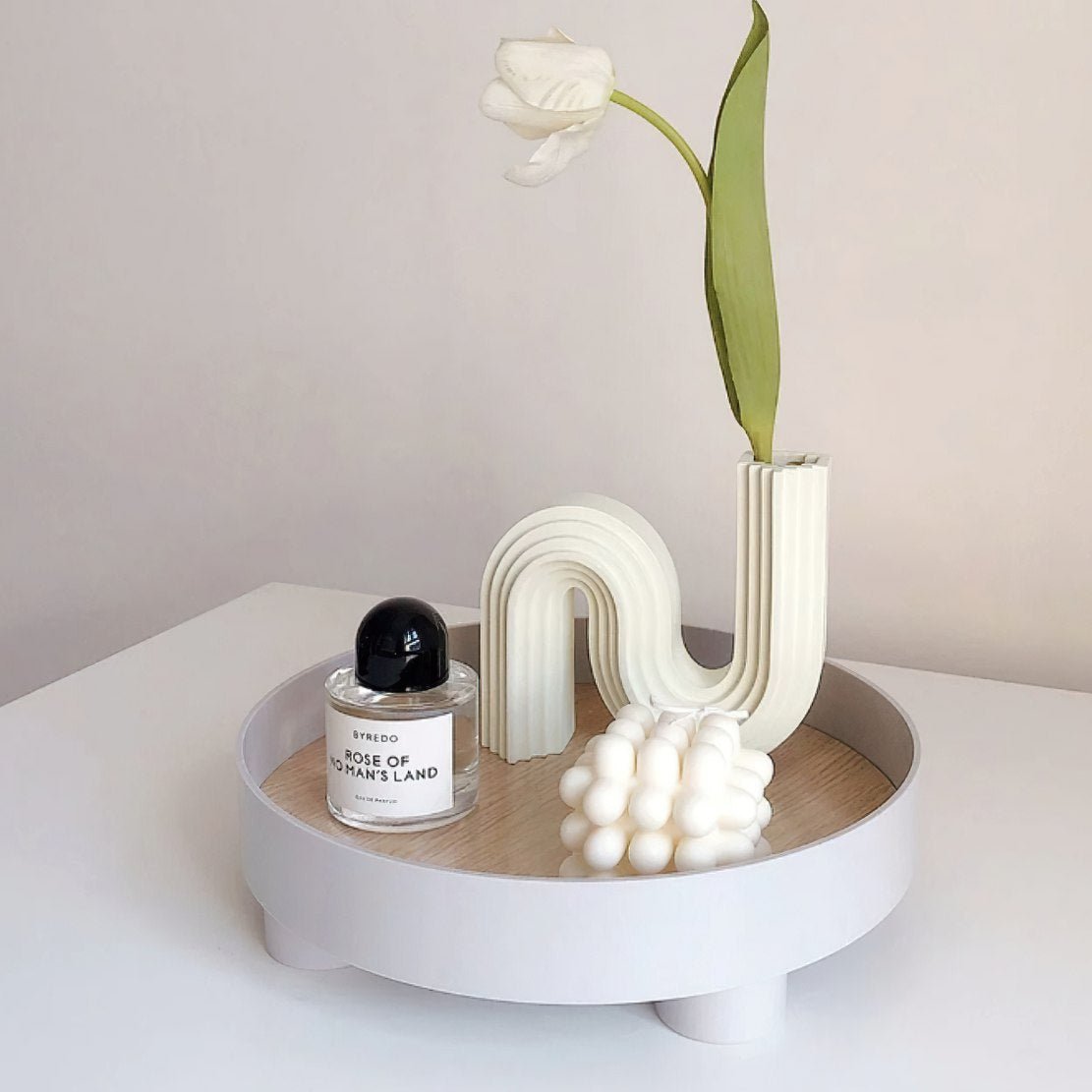 Nordic decorative elevated round storage tray, holding a perfume, a flower vase and white candle