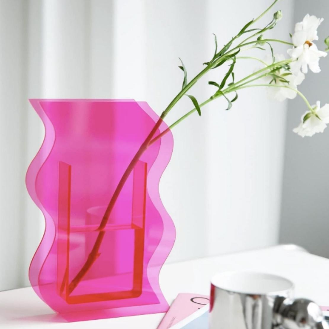 Pink, wavy acrylic decorative vase with white flowers