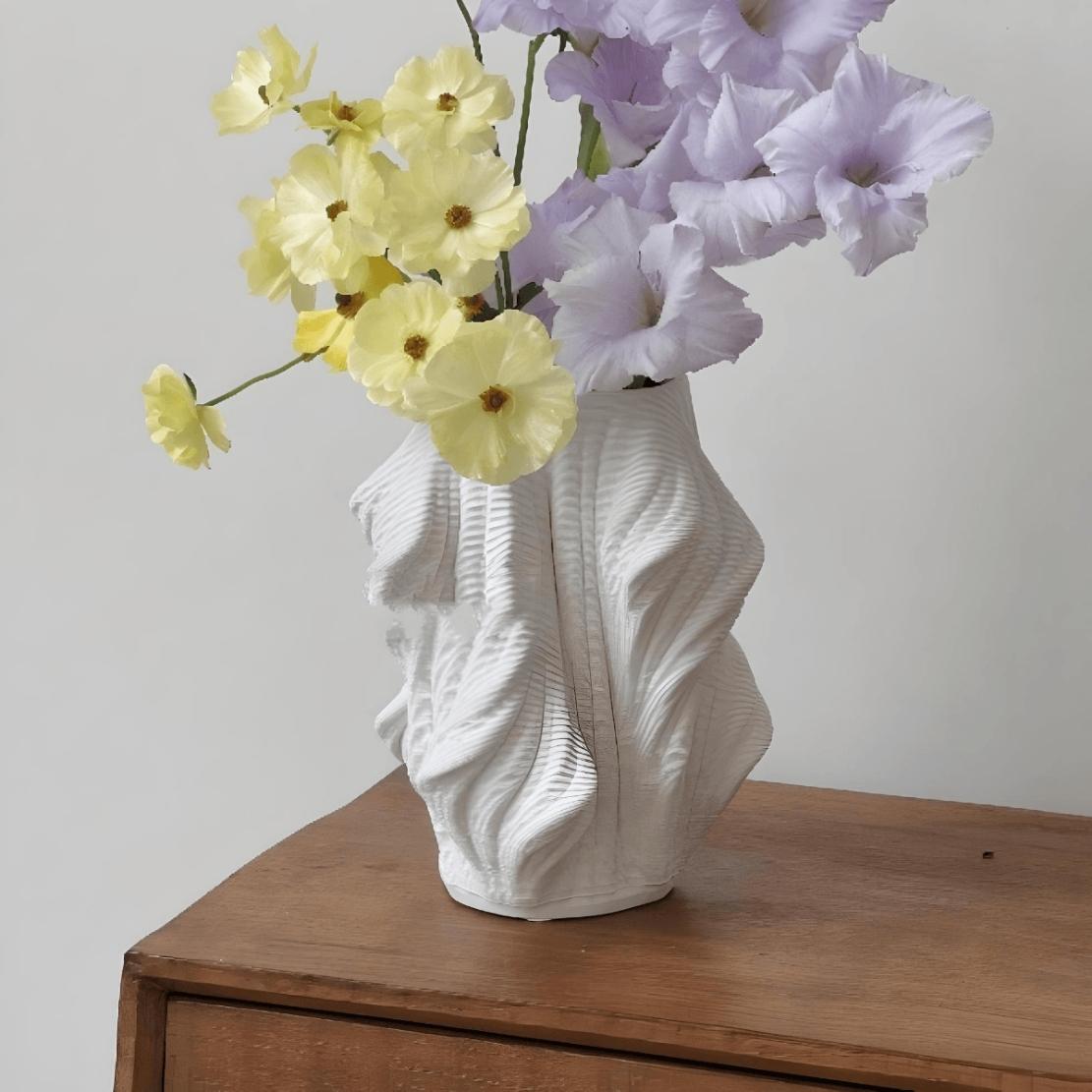 White, ceramic, wavy vase on wood shelf with flowers