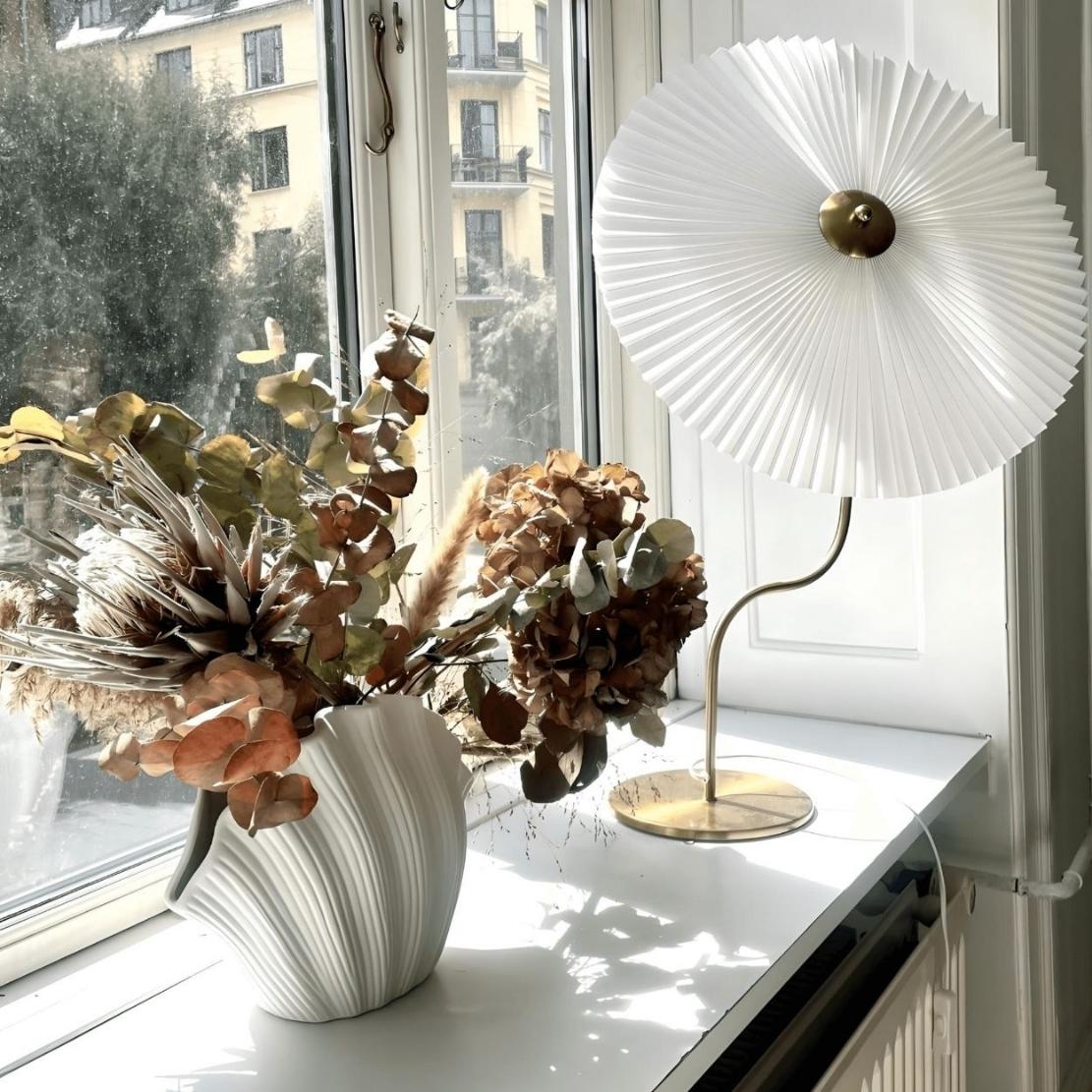 White ceramic shell vase with a dried flower bouquet and a white umbrella lamp