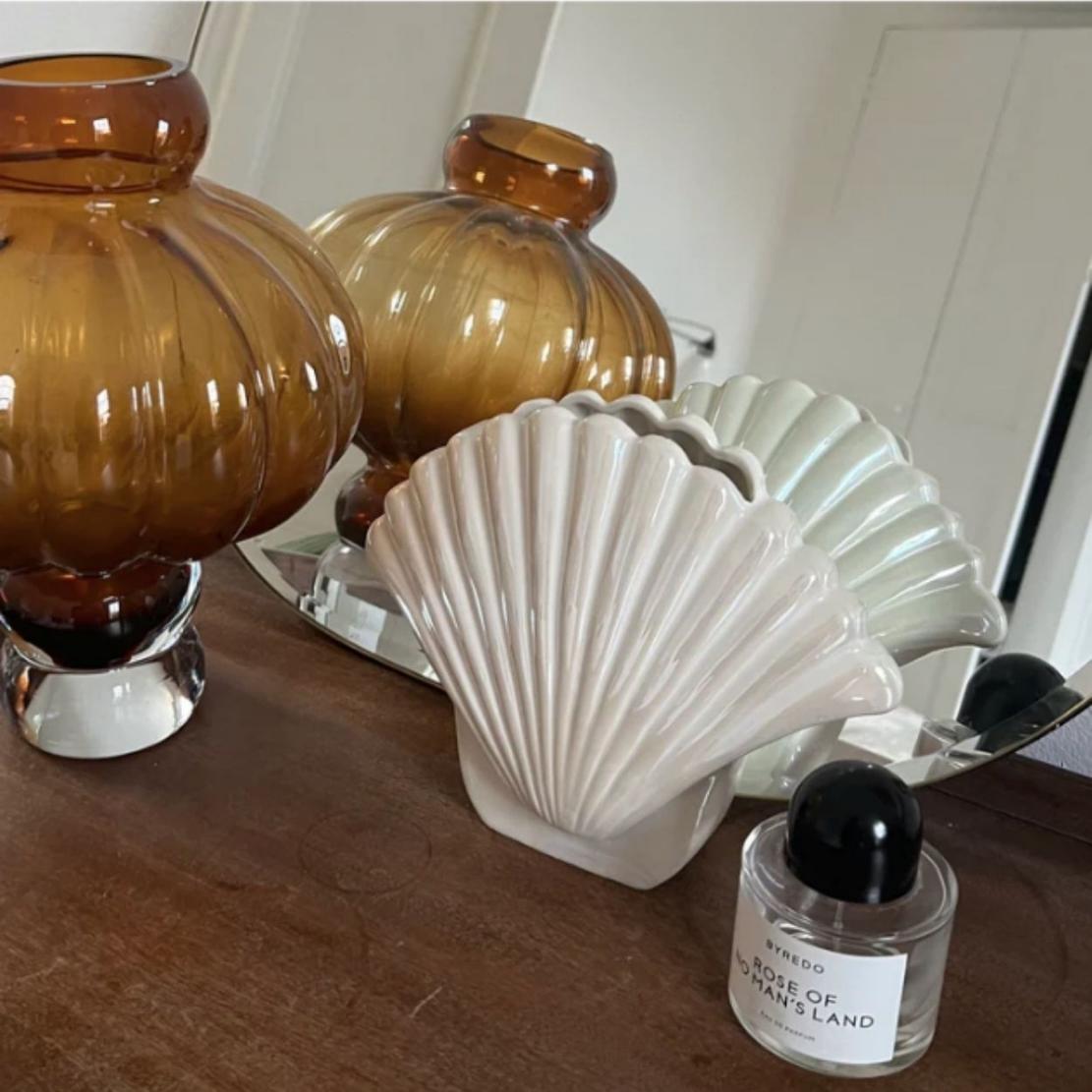 White, elegant ceramic shell vase on wood table