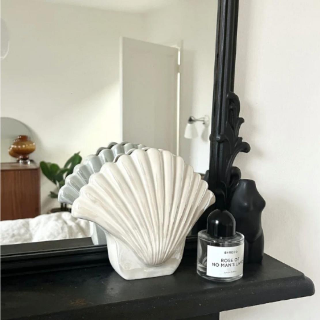 White, ceramic, elegant shell vase on black shelf
