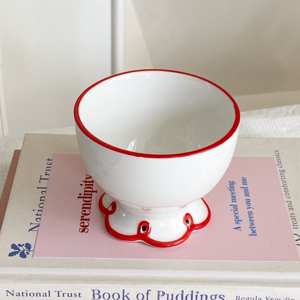 White, porcelain tea cup with red, flower rim