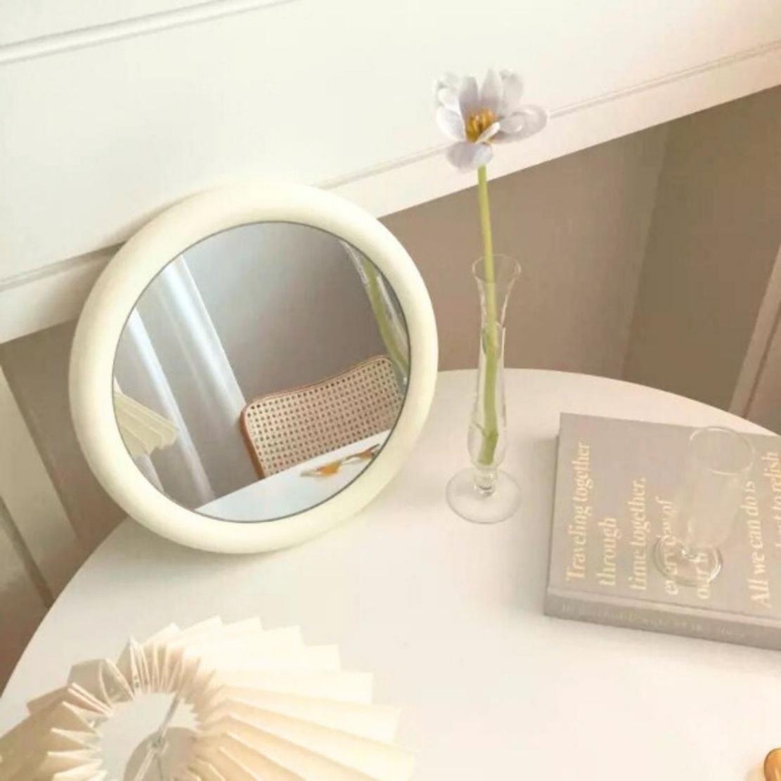 White, round frame decorative mirror on a table